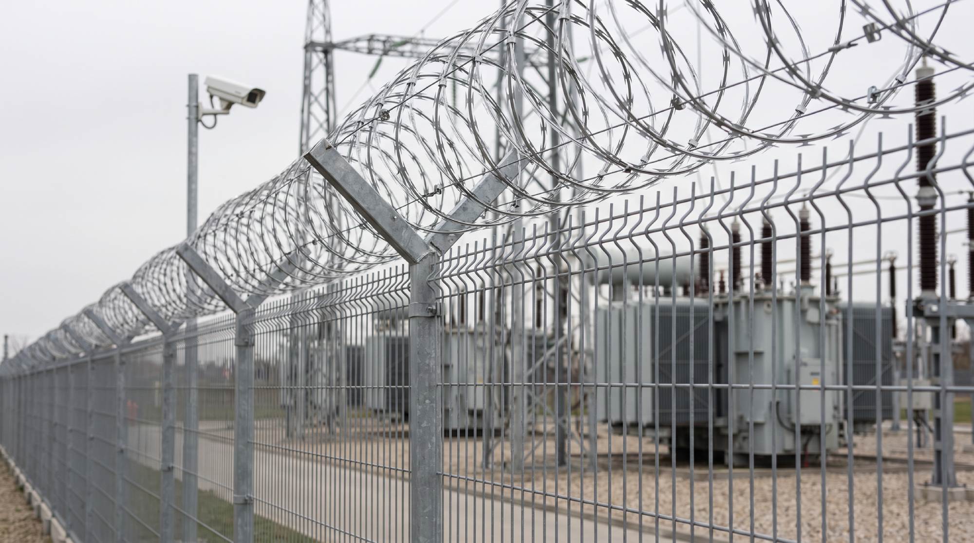 Warstwowe ogrodzenie ochronne obiektu energetycznego z panelami i agresywnym zwieńczeniem